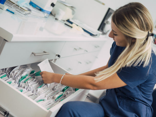A nurse is looking through a drawer full of papers